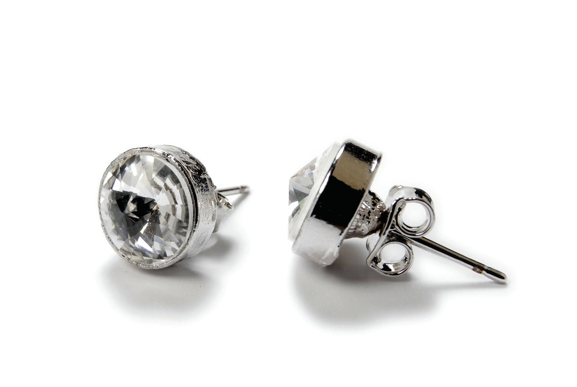 A pair of silver-colored round rhinestone stud earrings, designed for pierced ears, with a central clear rhinestone and metallic accents.