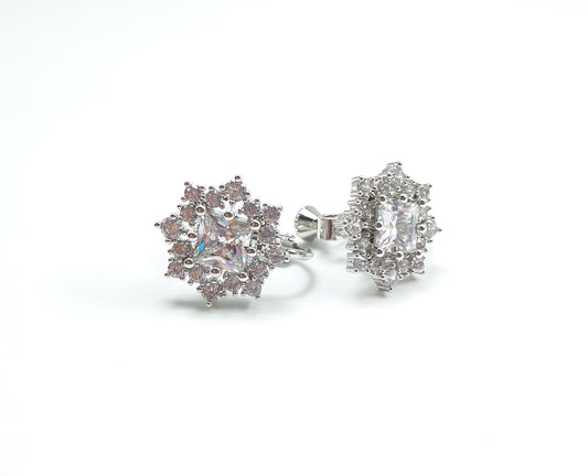 A pair of star-shaped clip-on earrings with a geometric pattern and embellishments.